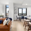 Open concept kitchen, living room space with a couch, dining table, and barstools at the counter.