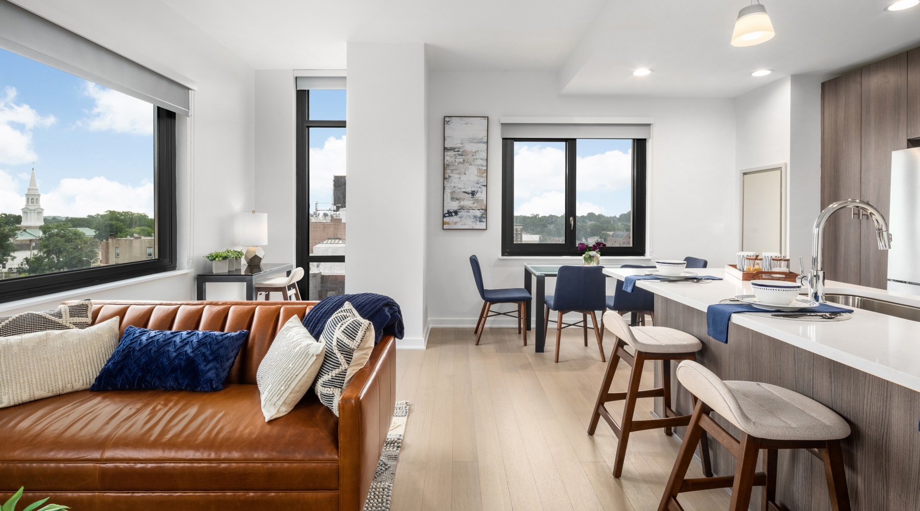 Open concept kitchen, living room space with a couch, dining table, and barstools at the counter.